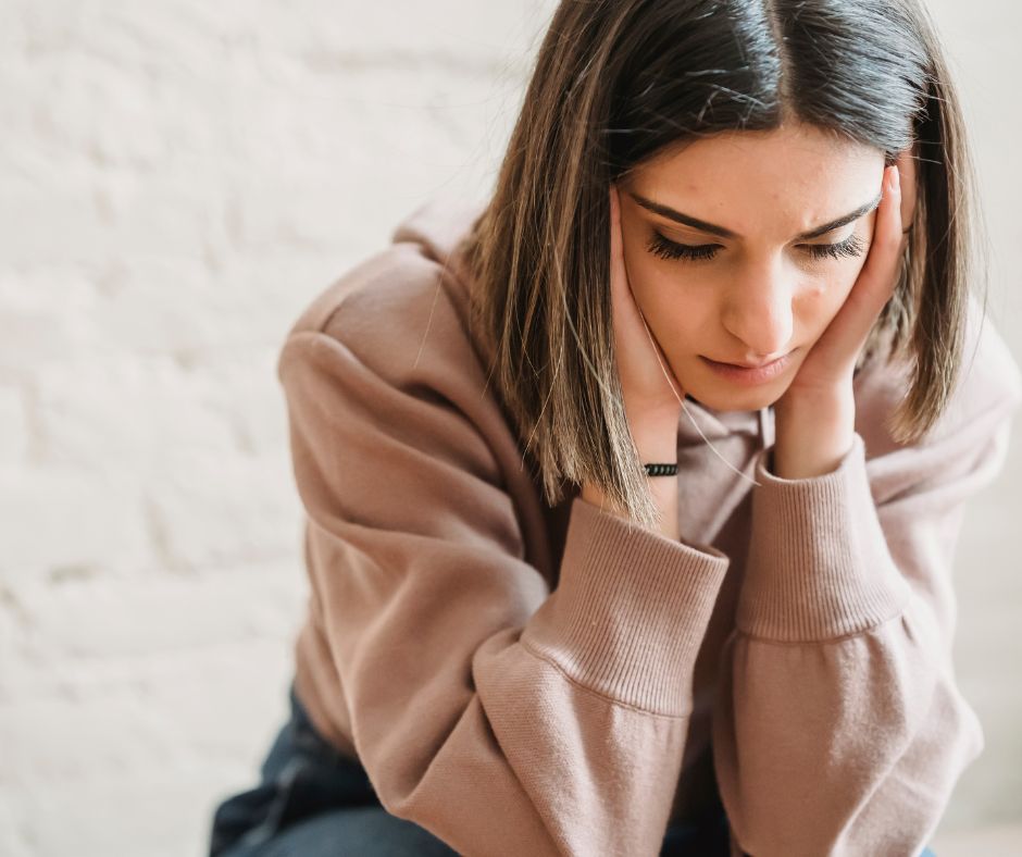 Une femme est en train de douter de soi la tête dans les mains